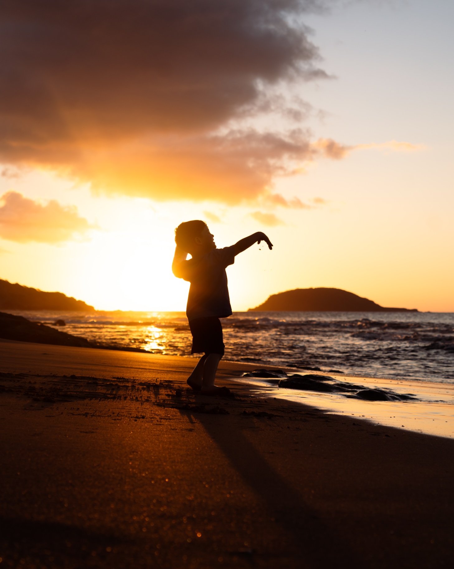 Enfant en silhouette jouant sur une plage dorée