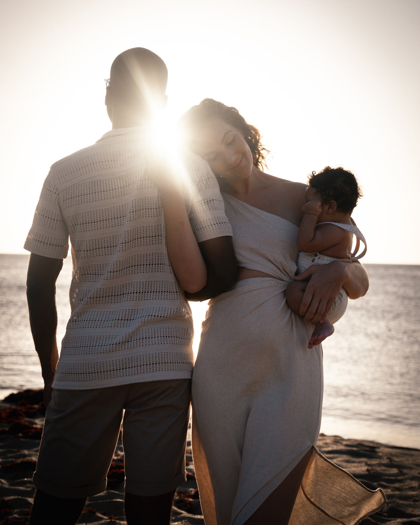 Famille contemplant l'océan au coucher du soleil