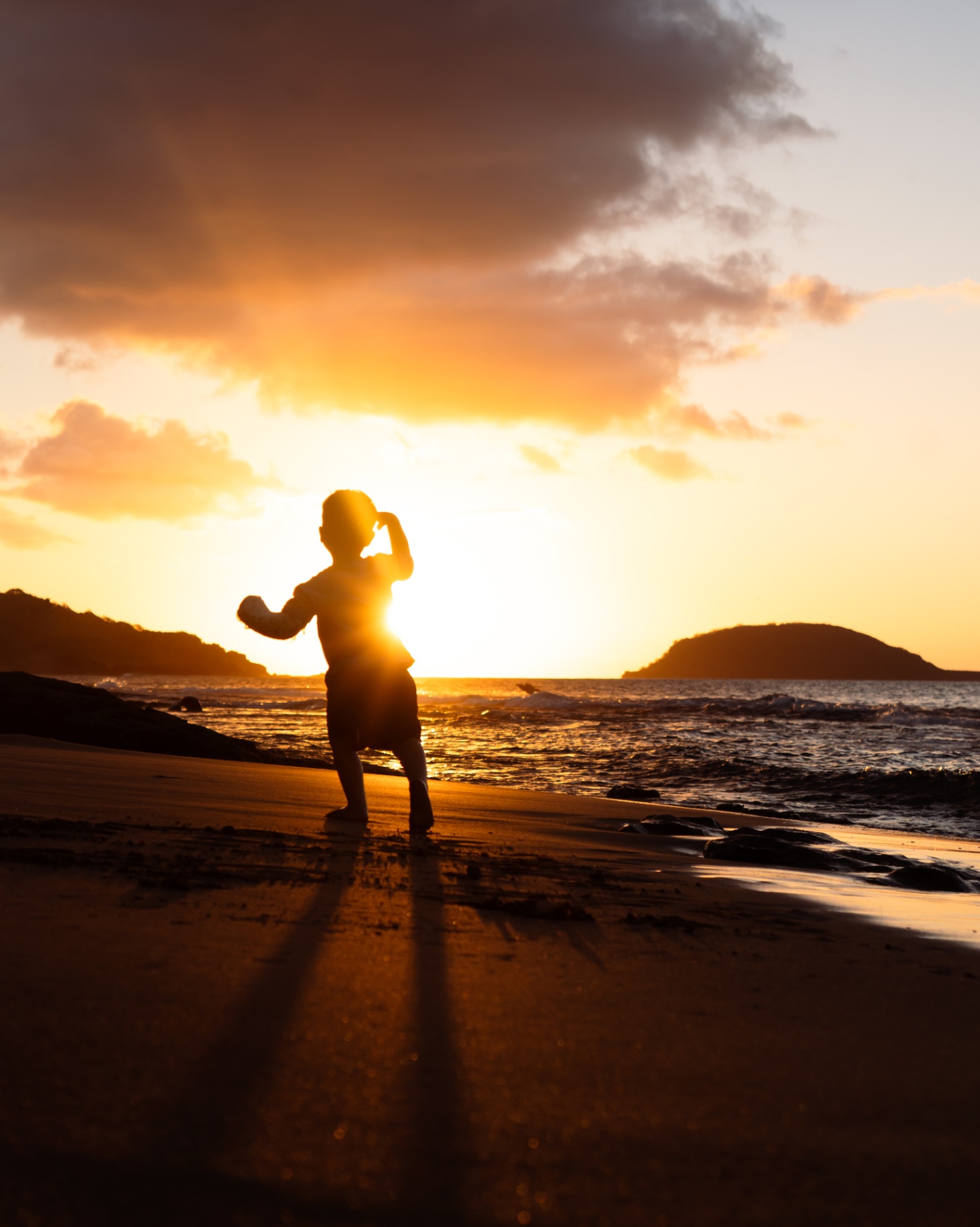 Enfant observant le soleil se coucher sur la mer