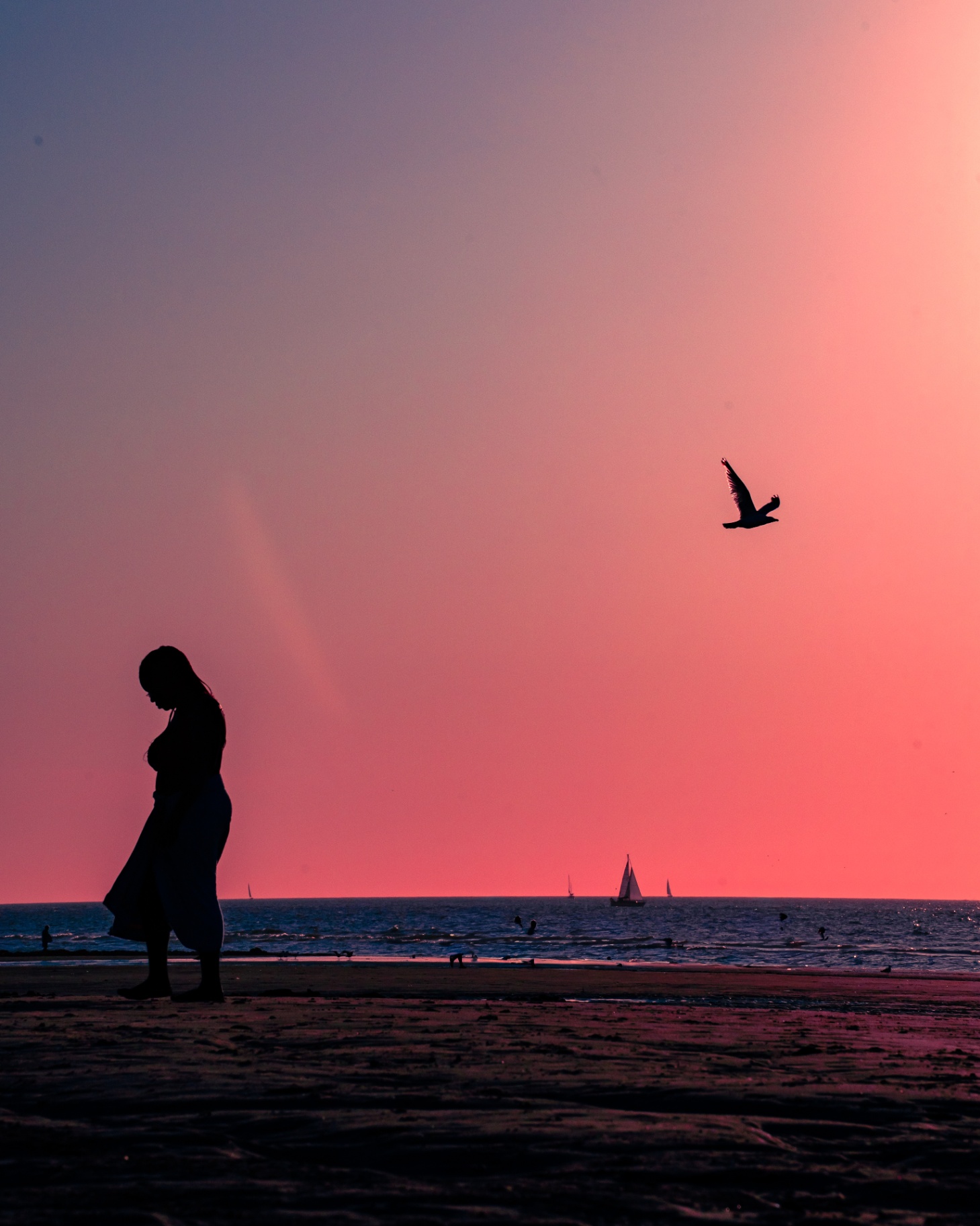 Silhouette d'une femme enceinte sur une plage au coucher du soleil