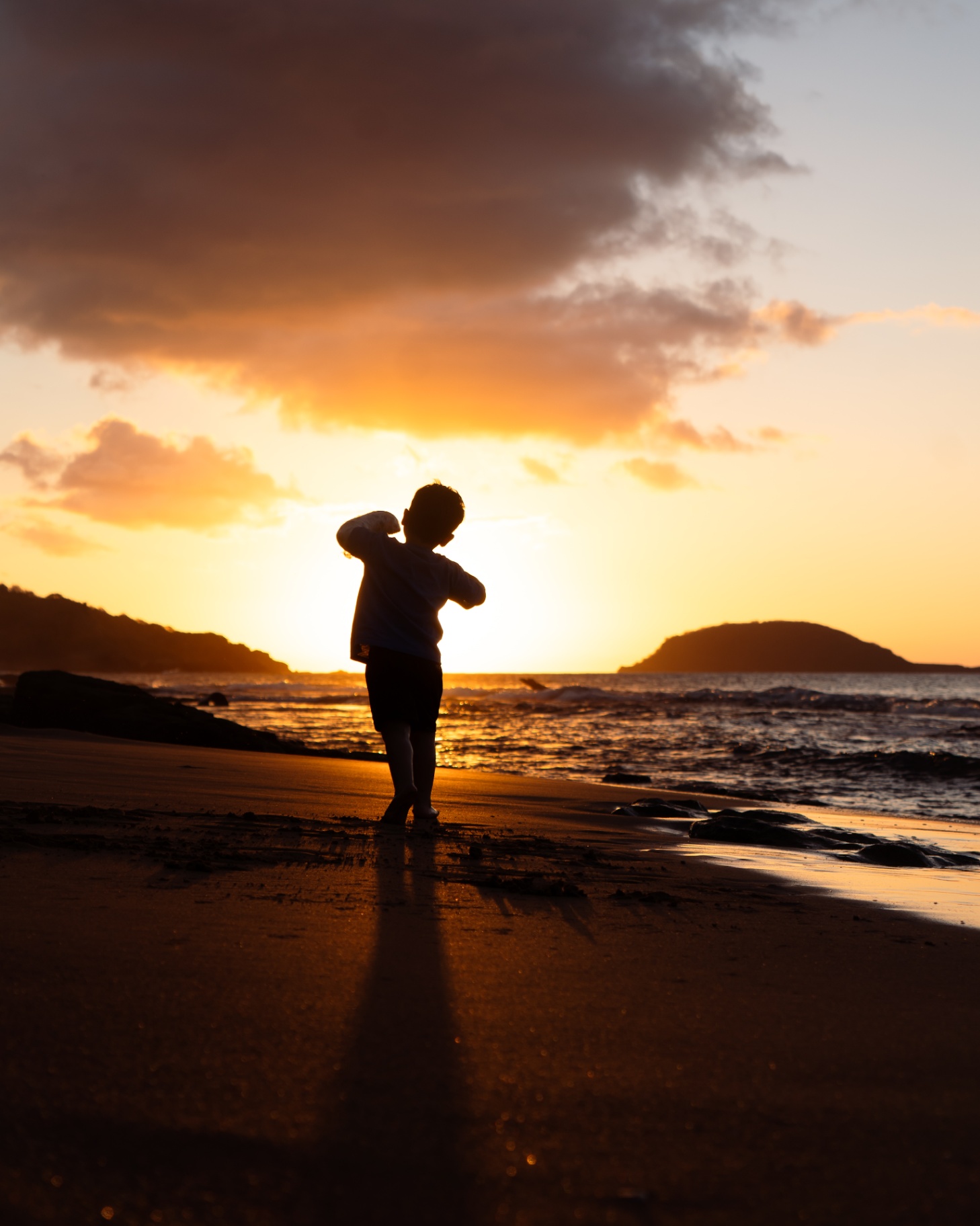 Enfant de dos face au soleil couchant sur la plage